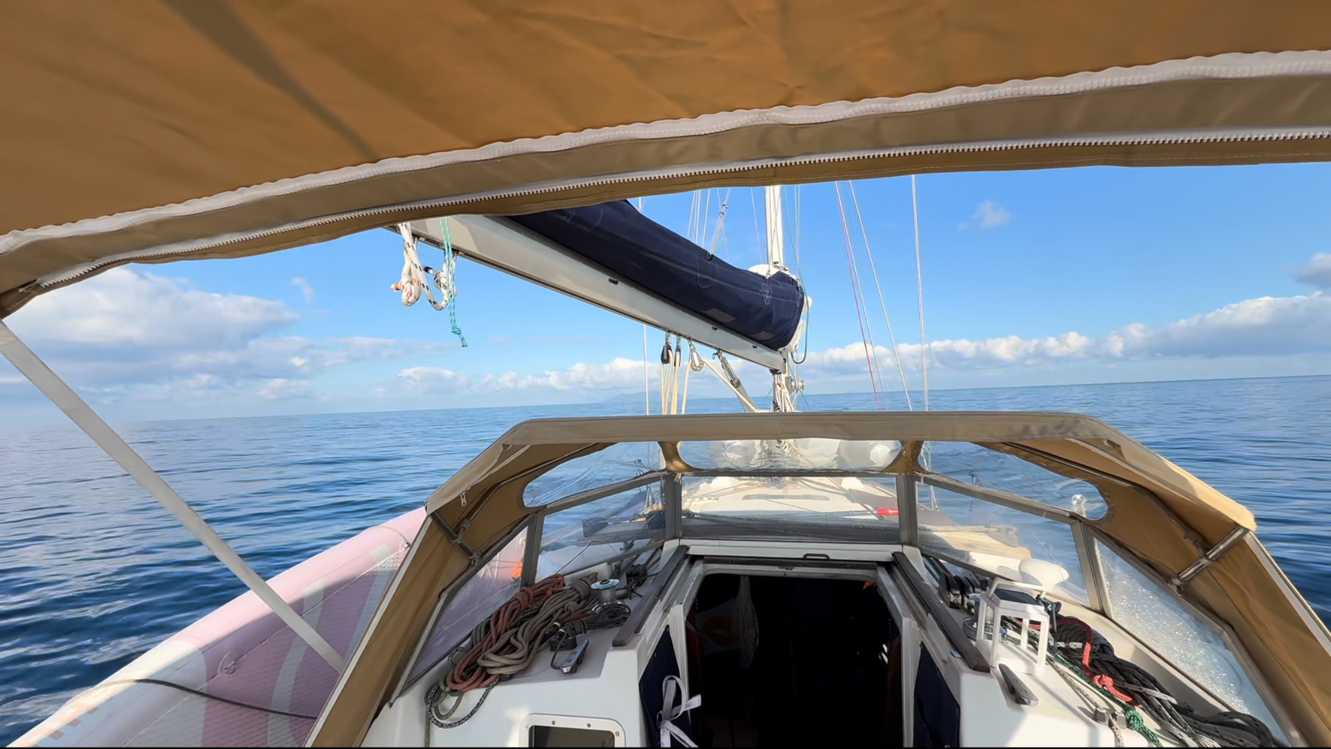 View forward from under the bimini over the sprayhood and calm sea